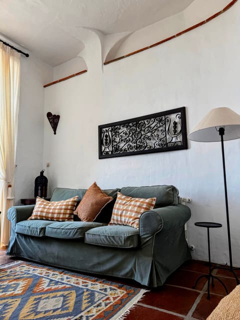 The living room of the Molino Escamillos apartment at Molino del Carmen, with patterned rugs and a green sofa